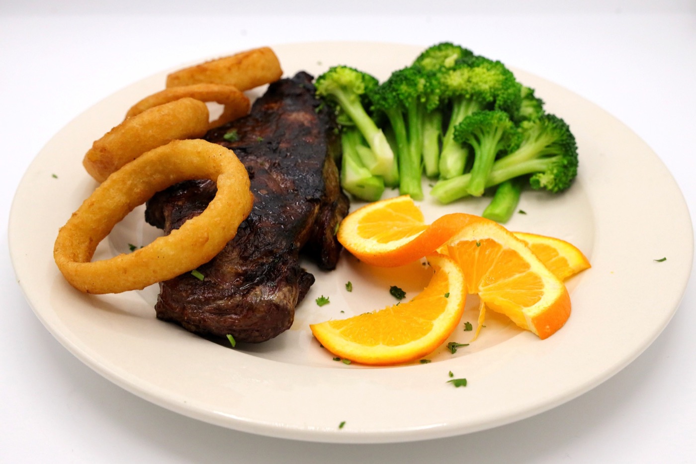 Steak dinner with broccoli, orange slices, and onion rings